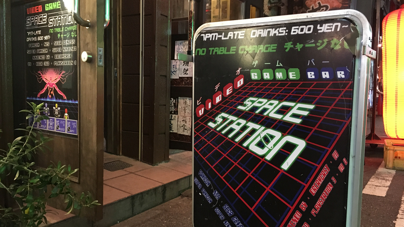 Bright signs on the street advertise the “video game bar,” Space Station.